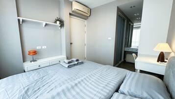 A hotel room with a bed, bedside table, lamp, and a wardrobe.