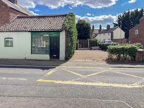 Un bâtiment avec un toit recouvert de tuiles, une porte verte et une fenêtre à carreaux.