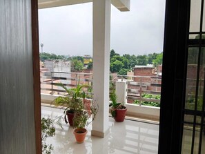 A balcony with potted plants and a view of a residential area. - Shri Shyam Gest House (Sultanpur)