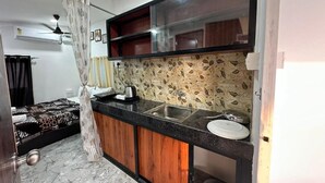 Una cocina compacta con encimera negra, armarios de madera, pileta integrada y un salpicadero con diseño.