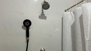 Une douche équipée d’un pommeau de douche à main et d’un robinet fixé au mur.