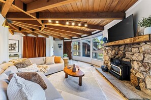 Una sala de estar moderna con una chimenea de piedra, un sofá grande y un televisor montado en la pared.