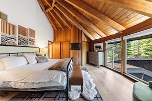 A bedroom with a large bed, wooden ceiling beams, a dresser, and a television. - Redwood Home | Sauna + Hot Tub | Near Lifts + Village | Roundhouse at Northstar (Truckee)