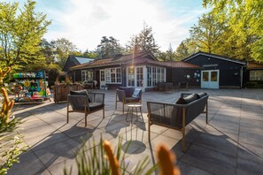 Eine Terrassenanlage mit Sitzgelegenheiten im Freien, ein Holzgebäude mit einem Ziegeldach und ein Schild, das auf einen Servicebereich hinweist.