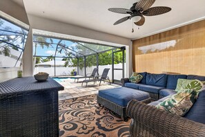 Eine sonnige Terrasse mit Pool, Sitzgelegenheit im Freien und Deckenventilator.