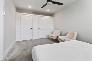A bedroom with a bed, two chairs, a wardrobe, and a ceiling fan. - Blue Ridge Views + Balcony + Two Living Rooms | Downtown | Tranquil River Home (Asheville)