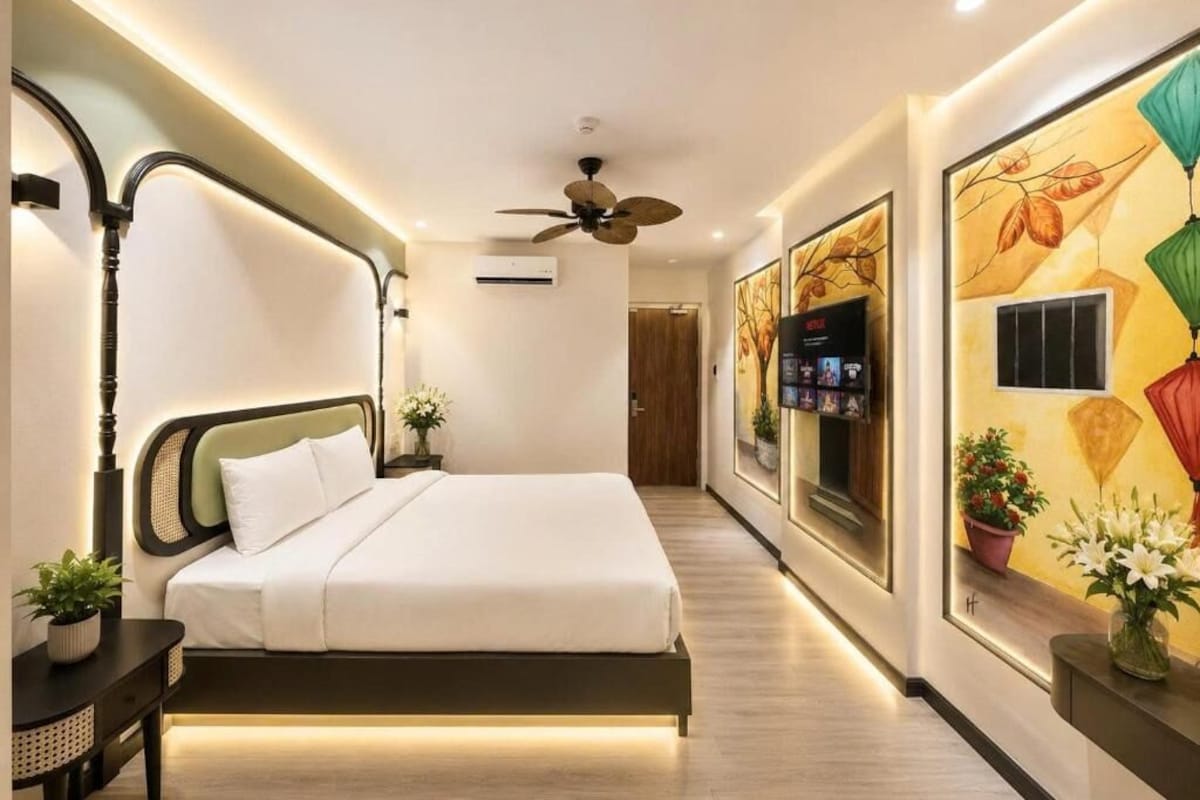 Ein modernes Hotelzimmer mit einem Bett, einem Deckenventilator, einem an der Wand montierten Fernseher und einer Wand mit floralem Dekor.