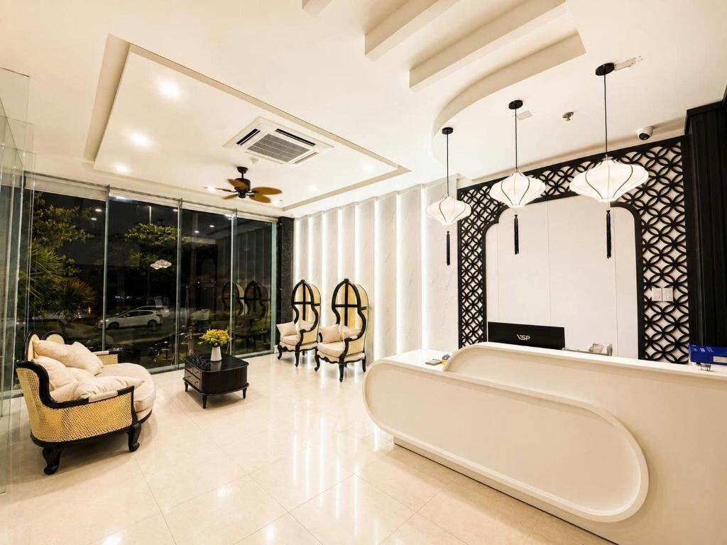 Un espace d’accueil moderne comprenant un comptoir de réception, un coin salon avec des fauteuils et une grande fenêtre offrant une vue dégagée.
