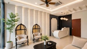 A modern living room with a ceiling fan, a sofa, a coffee table, and a decorative plant. - Asteria Ocean Residence (Da Nang)