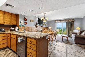 A modern kitchen with granite countertops, wooden cabinets, and a built-in dishwasher. - Smoky Views + Indoor Pool + Sauna & Spa | Near Park Trails | Bear Ridge (Gatlinburg)