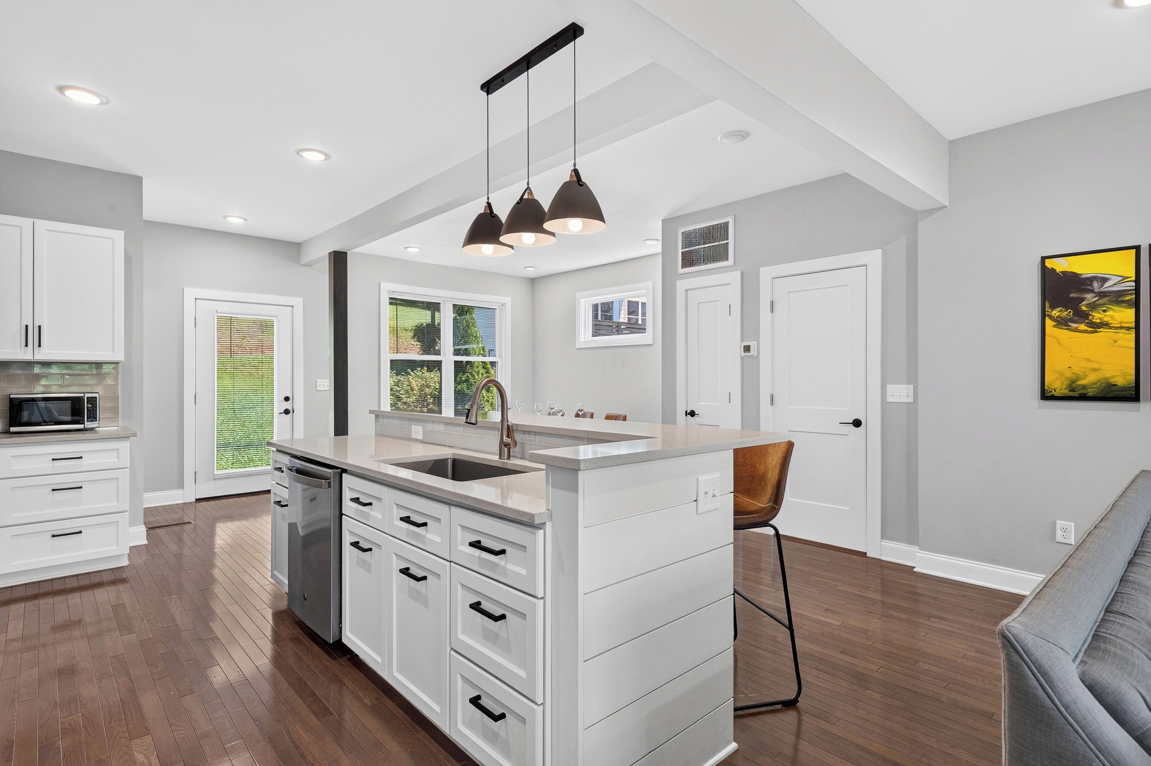 A modern kitchen with white cabinetry, a central island with a sink, and pendant lighting.
