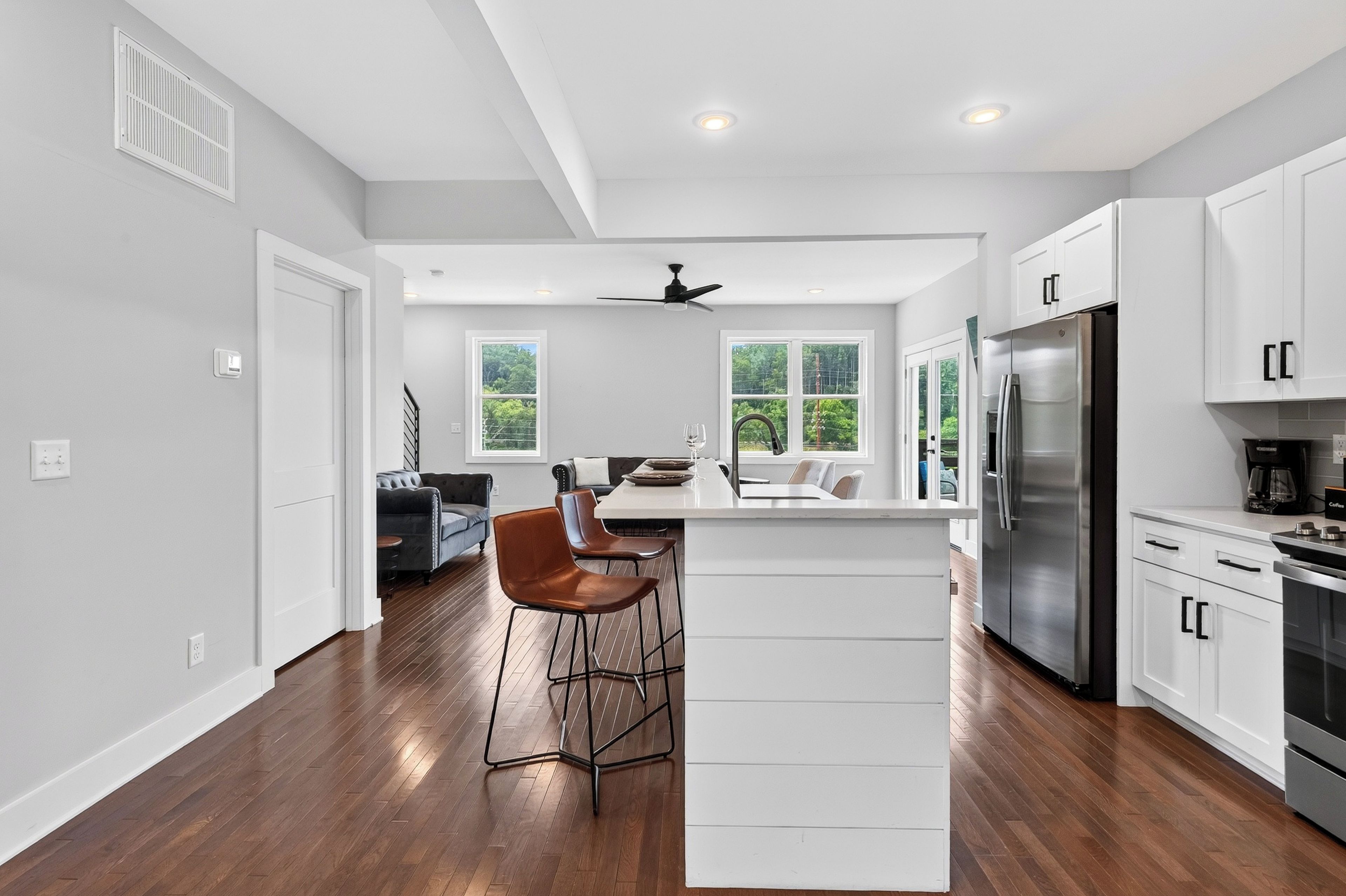 A modern kitchen with a central island, stainless steel appliances, and a dining area with a sofa and chairs.