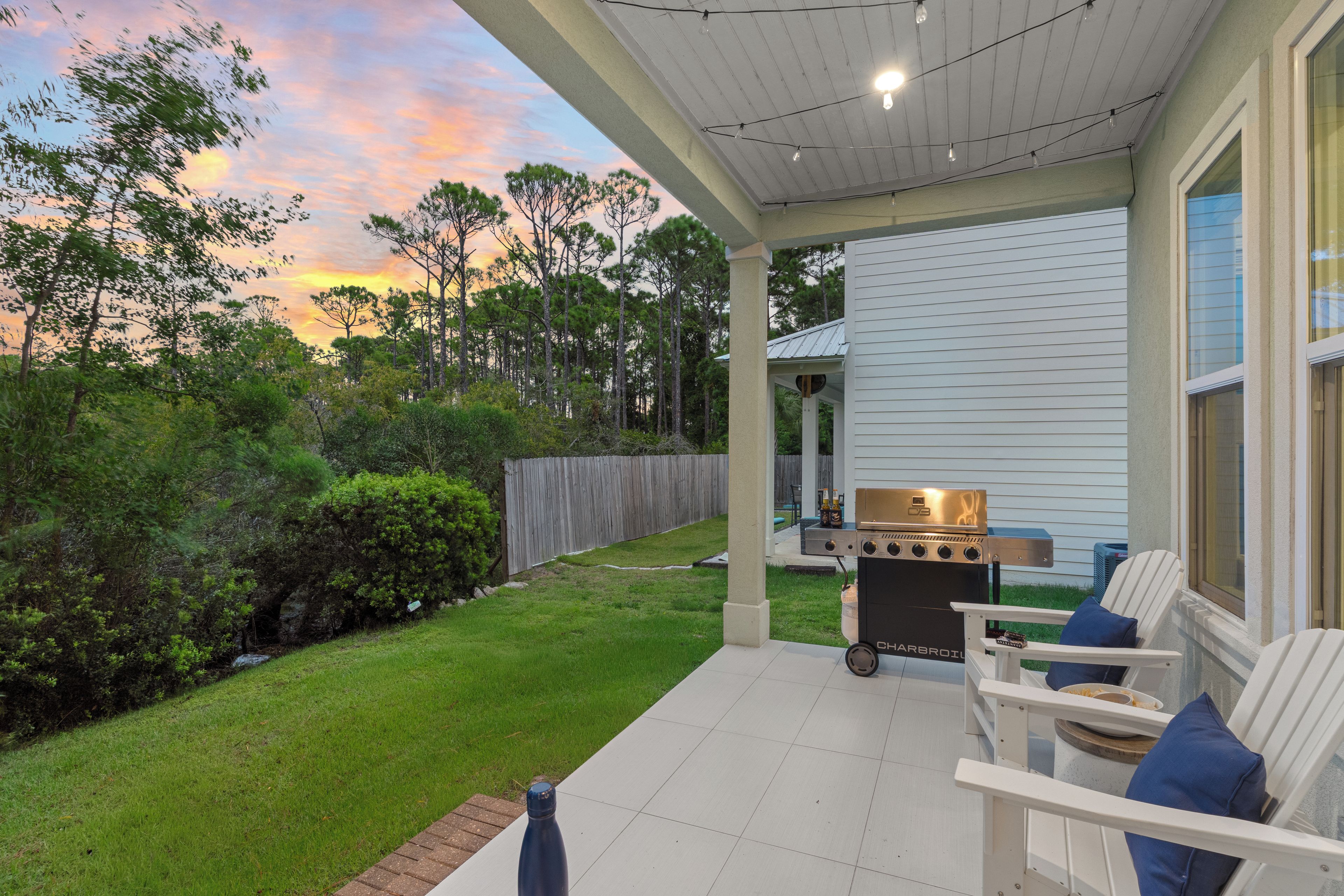 Covered porch with BBQ grill and Adirondack chairs.