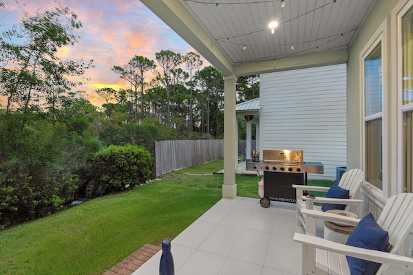 Covered porch with BBQ grill and Adirondack chairs.