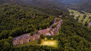 Eine Luftaufnahme eines Resorts mit mehreren Gebäuden, einem Golfplatz und bewaldeten Hügeln ringsherum.