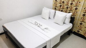 A single bed with white bedding and pillows, a black headboard, and a floral-patterned curtain. - Shalom View Homestay  (Kandy)