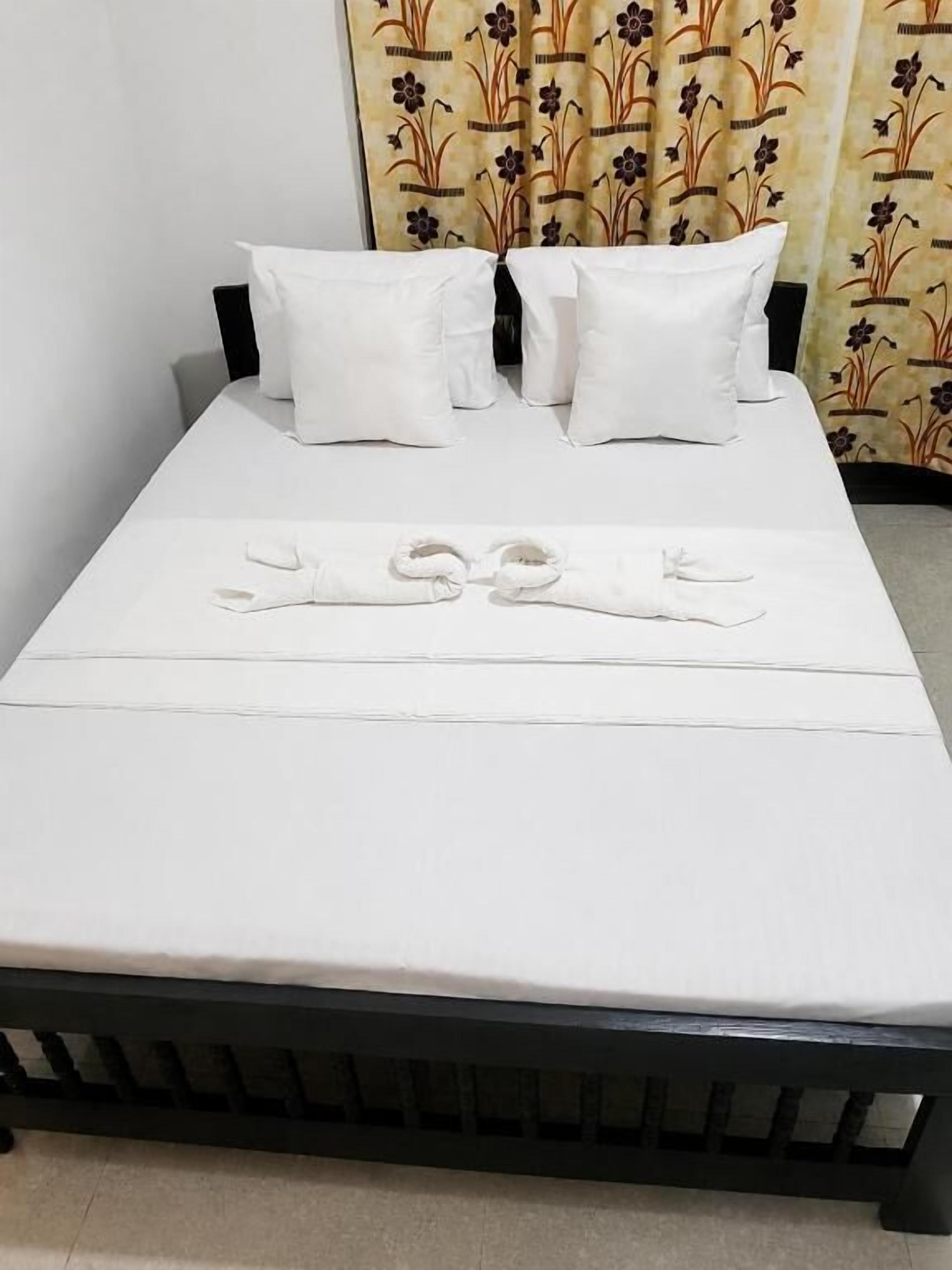 A bed with white bedding and a black frame, accompanied by two pillows.