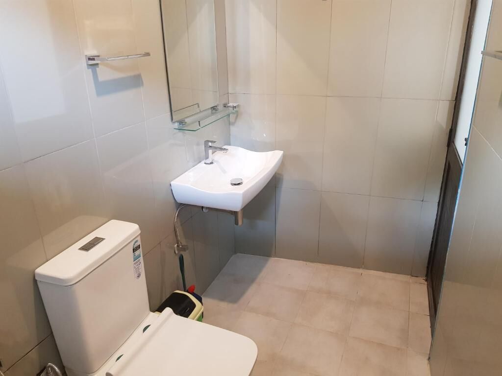 A small bathroom with a white sink, a toilet, and a glass shower enclosure.