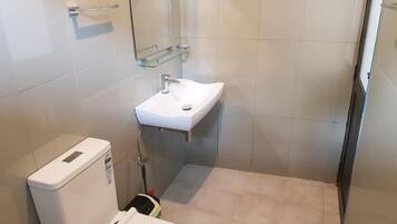 A small bathroom with a white sink, a toilet, and a glass shower enclosure.