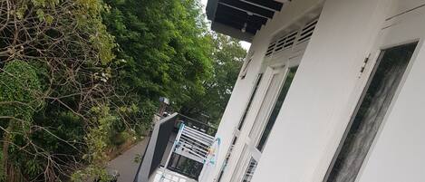 Un sendero estrecho bordeado por un edificio blanco con ventanas y un toldo negro.