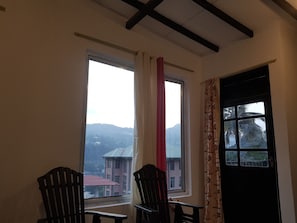 Una habitación con dos ventanas, una silla y una mesa.