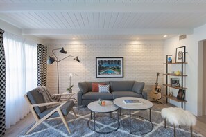 A living room with a sofa, two armchairs, a coffee table, a guitar, and a bookshelf. - The Weekend | 2 Suites • Boutique Stay in Palm Springs, Private Patio, Pool (Palm Springs)