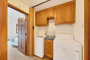 A laundry room with wooden cabinets, a washing machine, and a dryer. - Alpine Chalet + Decks + Game Room | Near Ski + Lake | Stillwood (Stateline)