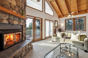 Una sala de estar acogedora con chimenea de piedra, un sofá y una mesa de centro de vidrio.
