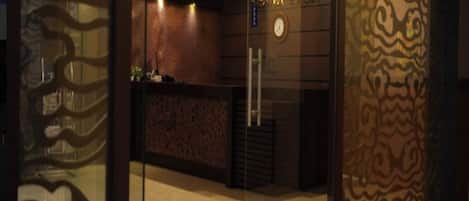 Una zona de recepción con mostrador, un reloj y un papel tapiz decorativo.