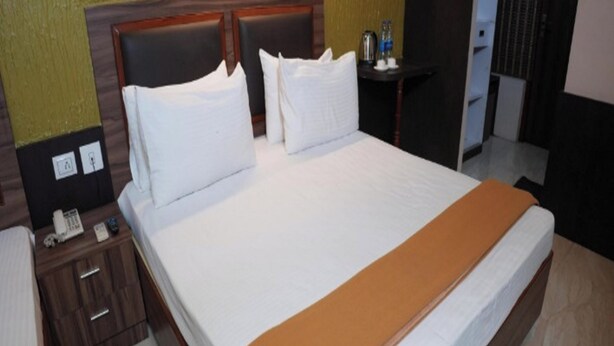 Una habitación de hotel con una cama grande, una mesita de noche con un teléfono y una lámpara.