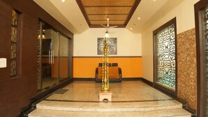Un vestíbulo de hotel con una escalera central, una recepción y una columna decorativa.