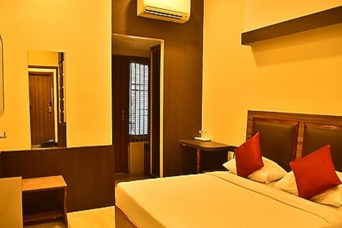 Una habitación de hotel con cama, escritorio, silla y aire acondicionado.