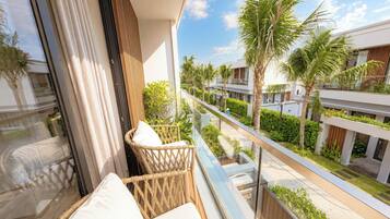 A balcony with wicker furniture and a view of a residential area with palm trees and modern buildings.