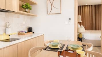 A modern kitchen with wooden cabinets, a countertop, and a dining area with a table set for two.