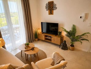 A living room with a television, a sofa, a coffee table, and potted plants. - Villa Irini Ocean View 2-bedroom apartment with AC in charming Fryni (Fryni)