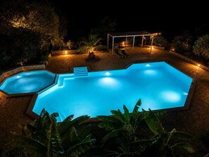 A swimming pool with a geometric shape, surrounded by stone walls and illuminated by ambient lighting. - Villa Irini Ocean View 2-bedroom apartment with AC in charming Fryni (Fryni)