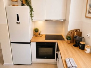 A compact kitchen with a Hisense refrigerator, a built-in oven, a coffee machine, and a small countertop with a cutting board and a basket. - Villa Irini Ocean View 2-bedroom apartment with AC in charming Fryni (Fryni)
