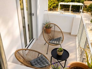 A balcony with two wicker chairs, a small round table, and potted plants. - Villa Irini Ocean View 2-bedroom apartment with AC in charming Fryni (Fryni)
