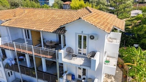 A multi-story building with balconies, a tiled roof, and outdoor seating areas. - Villa Irini Ocean View 2-bedroom apartment with AC in charming Fryni (Fryni)