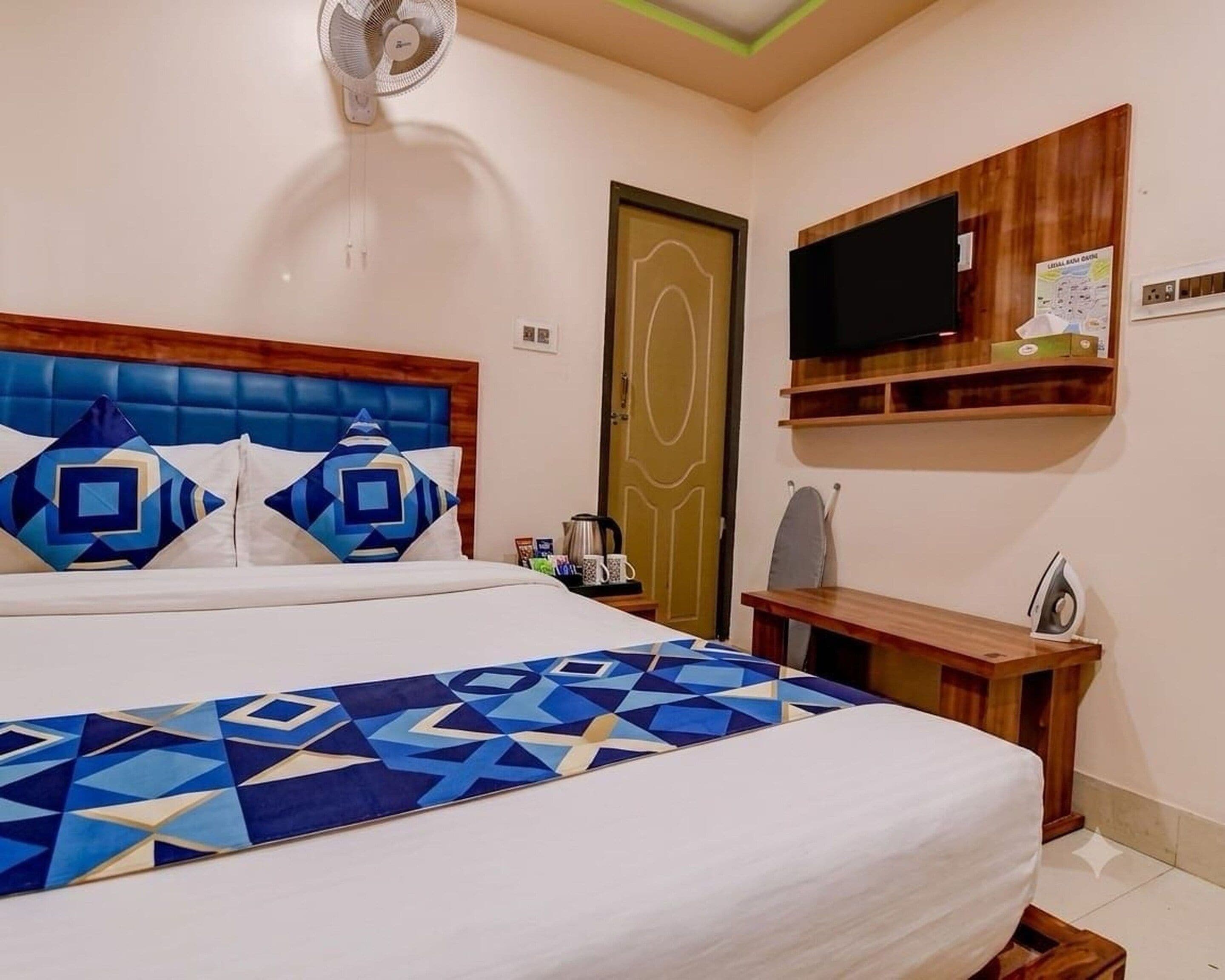 A bedroom with a bed, a television, a desk, and a door.