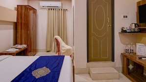 Ein Hotelzimmer mit Bett, Kleiderschrank, Klimaanlage, einer Tür und einem kleinen Tisch mit Wasserkocher und Tassen.