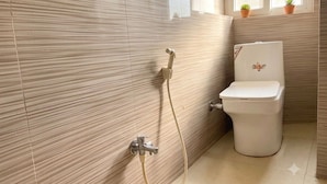 Ein Badezimmer mit Toilette, Dusche und einem Fenster mit Blumentöpfen.