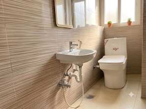 Un baño con lavamanos, inodoro y ventana con plantas en macetas.