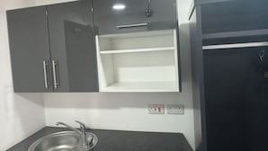 Cozinha equipada com micro-ondas embutido, pia com torneira e frigorífico.