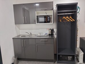 A compact kitchenette with a microwave, sink, and a small shelf. - Comfortable Accommodation in Nottingham (Nottingham)