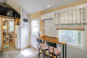 A compact kitchen with a dining area, featuring a refrigerator, a microwave, and a wooden table with two chairs.