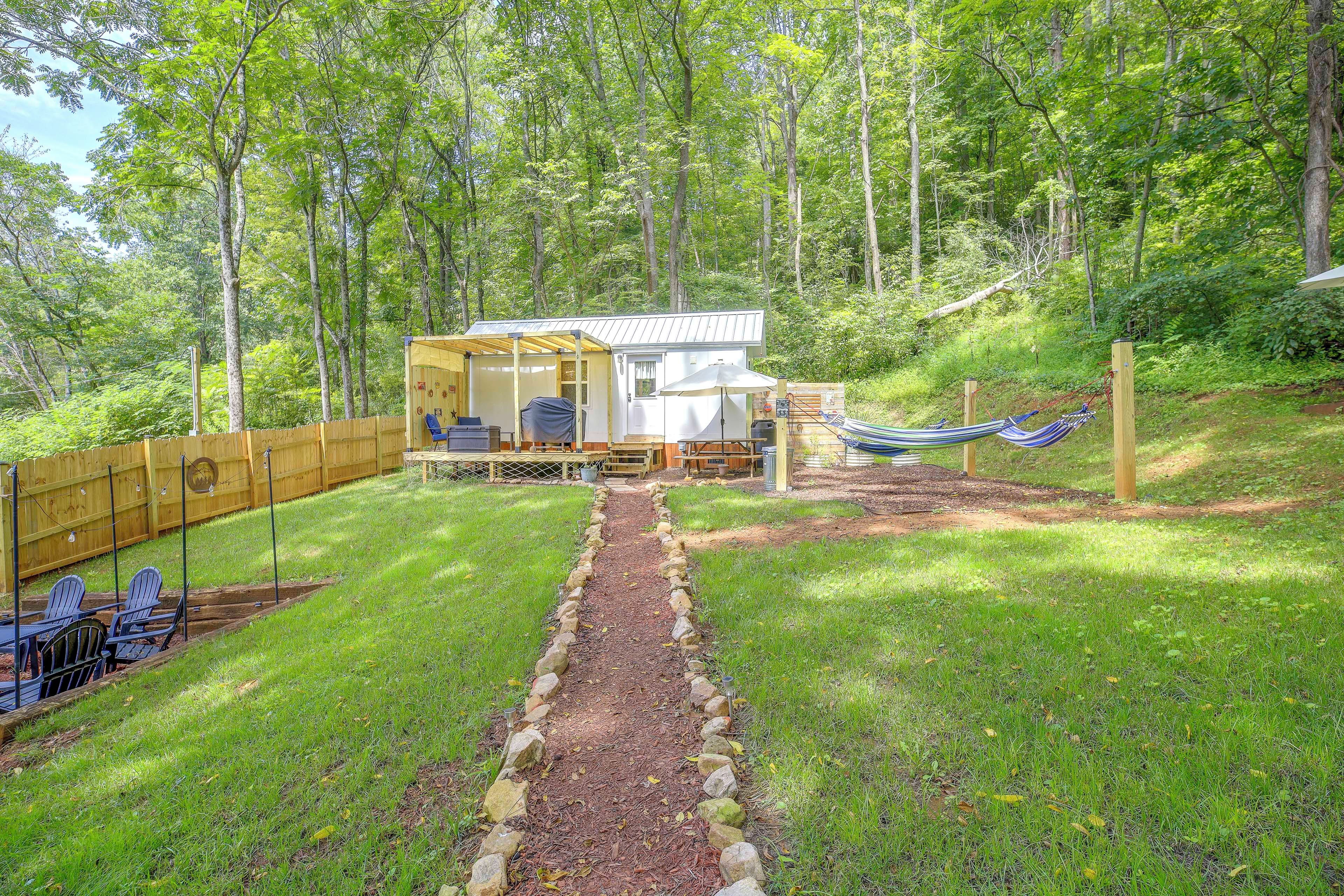 A cabin with a covered porch, a hammock, and a fenced yard.
