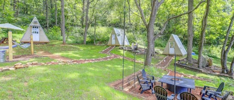 A campsite with multiple treehouses, a picnic table, and outdoor seating.