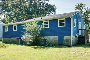 Une maison à deux étages, avec une façade bleue et un petit porche à l’avant.