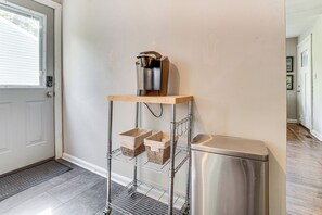 A metal rack with baskets and a coffee maker on top, a stainless steel trash bin, and a door with a window. - 5 Mi to Honky Tonk Hwy! Charming Escape w/ Porch (Nashville)